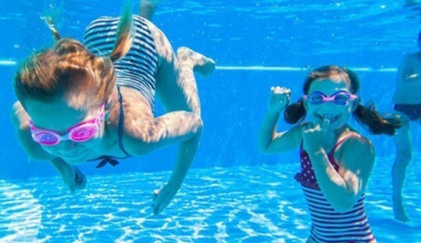 Zwei junge Mädchen bei einem Tauchgang in einem Schwimmbad